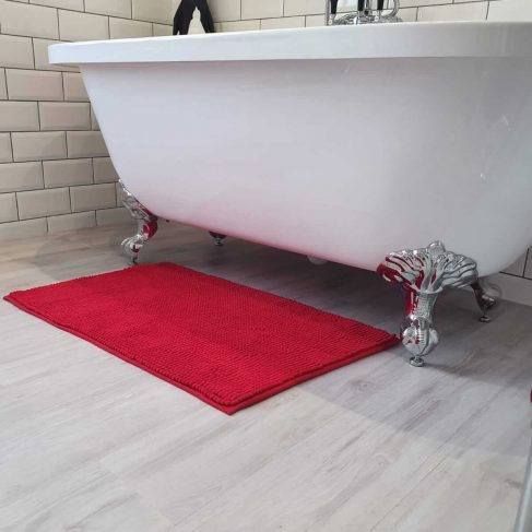 White rolltop bath, with red bath mat on a grey floor