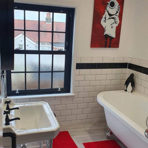 Black, white and red bathroom, with rolltop bath