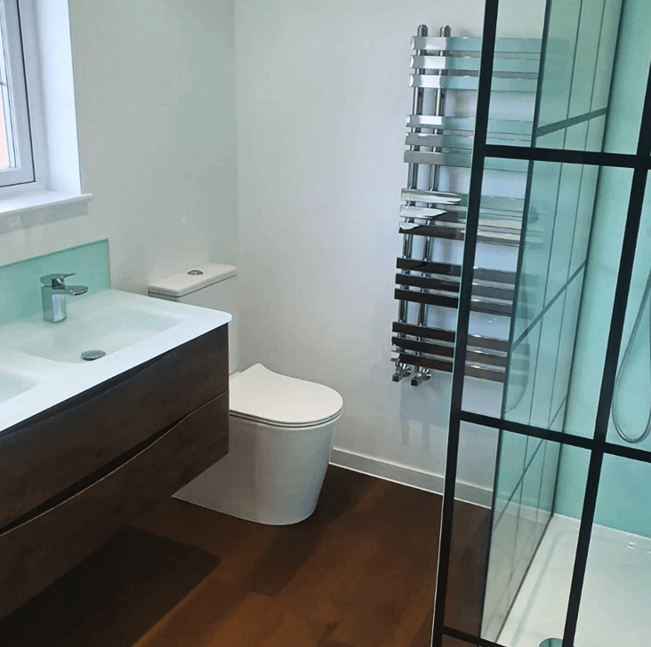 Image of the bathroom - double sink, toilet, shower and a silver radiator
