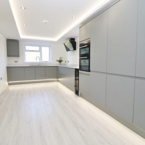 White and grey kitchen, white wall, grey units, with led lights at plinth level